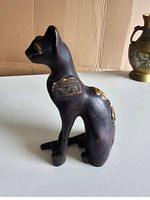 Side view of black Bastet cat sculpture showing gold details around neck and spine.
