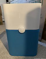 Front view of Blueair Pure 211+ air purifier with blue fabric cover and white top section, showing Blueair logo on front center.