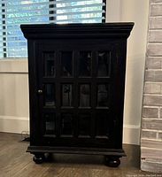 Front view of dark wood cabinet with closed door showing 12 glass panels.