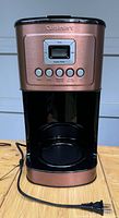 Front view of copper-colored Cuisinart coffee maker with control panel and power cord visible