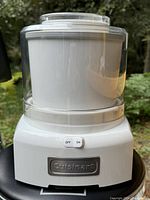 Front view of the white Cuisinart ice cream maker showing the on/off switch and transparent lid.