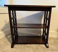 Front view showing the full office table structure with three shelves and Craftsman style side supports.