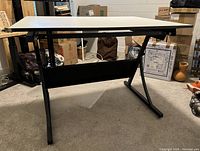 Front view of the Safeco drawing table showing white rectangular MDF top and sturdy black metal base with wide feet for support.