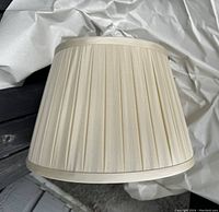 Side view of cream or ivory silk pleated lampshade showing fabric texture and shape.