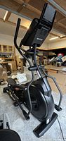 Side angle view of Sole Fitness E25 elliptical trainer showing the console, handles, and flywheel casing.