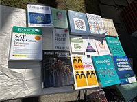 Photo showing an assortment of 15 educational books laid out on a surface including SAT Study Guide, General Chemistry, Human Physiology, and more.