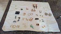 Full layout of the earrings collection showing all items on white cloth background