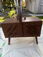 Closed wooden expandable sewing box on fold-out legs