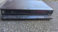 Front and slightly angled top view of the black Hitachi VHS recorder showing control buttons and slot for VHS tape.