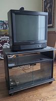 Front view of the Sony Trinitron 20-inch CRT TV on top of the TV stand, showing screen and lower speaker area clearly.