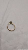 Full ring showing thin gold band and crown-like prong setting from the side, plain background.
