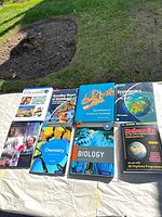 Photo showing 8 textbooks laid out on grass outdoors: D'accord! 3 French book, Decoding Theory of Knowledge for the IB Diploma, Quantitative Chemical Analysis, Economics for the IB Diploma, Civics in Action, Chemistry for the IB Diploma (Oxford), Biology for the IB Diploma (Oxford), Mathematics SL for IB Diploma