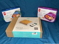 Photo showing two President's Choice bento box containers (one with blue lid and one with purple lid) alongside a Prepd Pack bamboo lunch container in its original packaging.