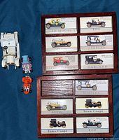 Top-down view showing the wooden display hanger with labeled compartments and two additional toy vehicles next to it.