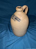 Full side view showing stamped text on pottery jug.