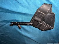 Scott Little Goose single caliper archery release with leather holster lying on blue fabric background