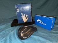 The black HandShoe ergonomic wireless mouse displayed with original retail box and user manual.