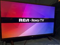 Front view of RCA Roku 32" Smart TV turned on displaying RCA Roku logo