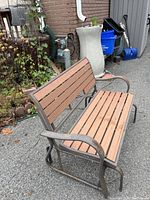 Side view of outdoor rocking bench showing metal curved armrests and wooden slats on seat and back.