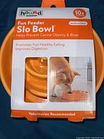 Front packaging of the orange Outward Hound Fun Feeder Slo Bowl in box showing branding, dog image, and product benefits.