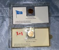 Two commemorative Canadian one dollar coins in plastic holders with printed descriptive cards.