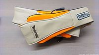 Soft beige and orange fabric neck and back massager with wired remote control and visible control buttons.