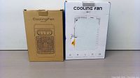 Two product boxes for portable cooling fans, one brown labeled CoolingFan with control panel image, other white box labeled Cooling Fan AB-1