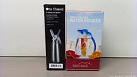 Photo of boxed Otis Classic whipped cream dispenser and boxed Misc Home fruit infuser water pitcher