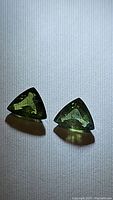 Close-up of the pair of natural green trillion cut sapphires showing shape and color.