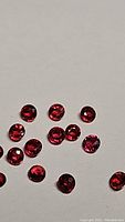 Close-up view of round faceted natural blood red rubies with rich clarity and vibrant red color on white background.