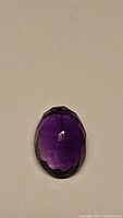 Top view of the oval cut purple amethyst gemstone showing faceting and color