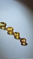 Four oval cut sapphires in deep yellow-orange tones laid out in a row on white surface