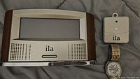 Front view of ILA talking clock, external temperature sensor, and Five Senses atomic talking watch with silver-tone dial and stainless steel band.