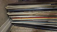 Side view of stacked vinyl album sleeves piled horizontally, showing various classical and children's music albums from the 1960s and 70s.