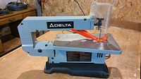 Front side view of the Delta scroll saw showing body, table surface, and blade guard.