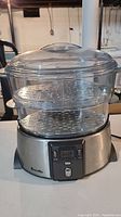Front view of Breville food steamer showing double-tiered clear plastic steaming baskets and stainless steel base.