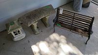 Photo showing three items together: a plaster and plastic solar lantern, a concrete curved garden bench in three pieces, and a small ornamental wrought-iron bench frame with rotted wood parts.