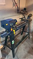 Front left perspective of lathe on stand against basement wall