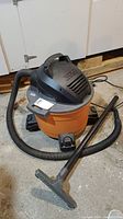 Rigid shop vacuum with hose and attachment on concrete floor