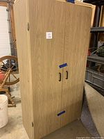 Closed view of a large melamine wood look cabinet with two black handles and wood grain finish.