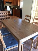 Dining table with four chairs and grey cushions in kitchen setting