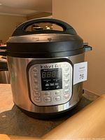 Metallic Instant Pot pressure cooker with black lid and handle shown from an angle, displaying the full appliance.
