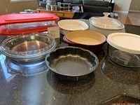 Photo showing all baking items arranged on a dark countertop, including Pyrex, Corningware, Pampered Chef, Anchor Hocking items