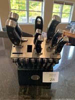 Full front view of the Remy Olivier wooden knife block containing 15 knives and 1 sharpener displayed on a kitchen counter