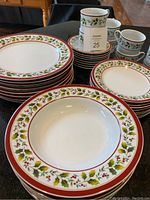 Set of dinner plates, soup bowls, side/dessert plates, cups, and saucers with Holly Berry pattern showing holly leaves and red berries