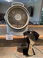 Photo showing Honeywell oscillating fan front view with swirl grille design and Ecofan wood stove fan in front
