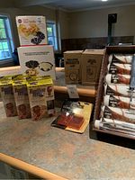 Various boxed household items on countertop with mosquito lamps, furniture feet packages, tortilla pans and brush heads visible
