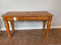 Front view of the pine wood console table showing single drawer and turned legs