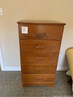 Front view of the dresser showing all five drawers with integrated wooden handles and surface wear.