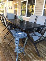 Full view of wrought iron dining table with six chairs and side table on deck.